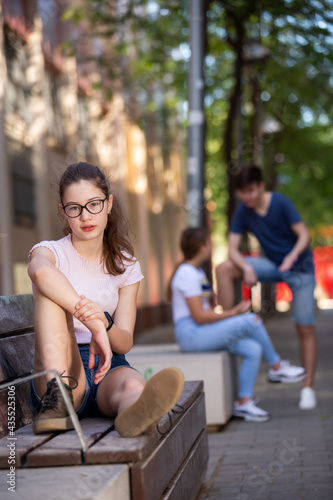 Portrait of pretty teenage girl with glasses on park bench