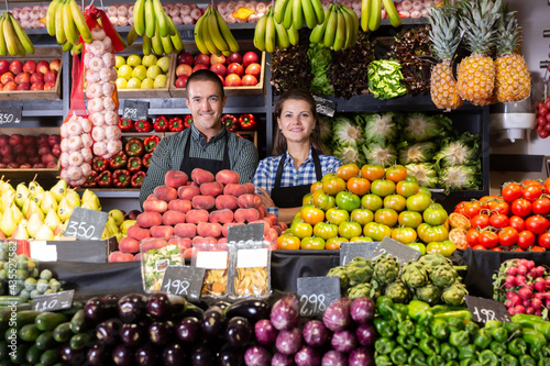 Positive male and female shop assistants in vegetable shop