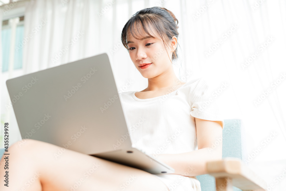 portrait of young girl sitting on sofa at home using laptop portrait of young girl sitting on sofa at home using laptop