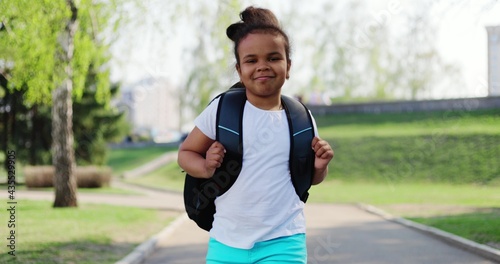 schoolgirl with a backpack runs home in the park from her school dream on a sunny day. children learning education concept.