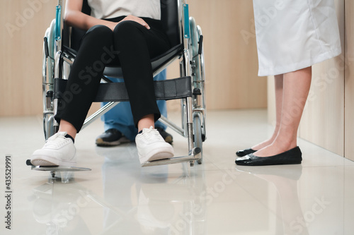 Close up shot in lower body part of patient on wheelchair with female doctor in white gown. Health care concept of hospital industry