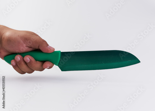 Mano de hombre sosteniendo un cuchillo de cocina de color verde sobre un fondo blanco