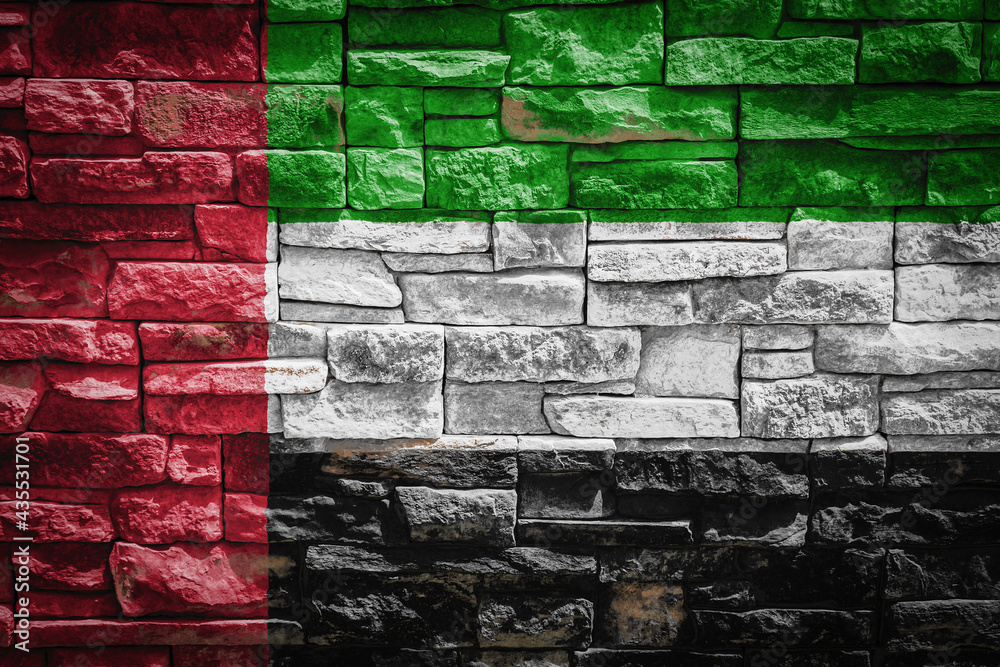 National flag of United Arab Emirates on stone wall background.The concept of national pride and symbol of the country. Flag banner on stone texture background. National flag of United Arab Emirates on stone wall background.The concept of national pride and symbol of the country. Flag banner on stone texture background.
