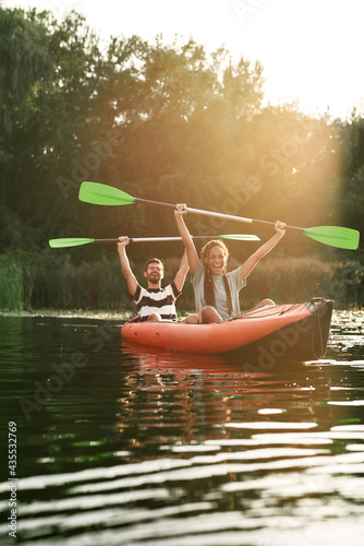 Couple of excited friends having fun while kayaking in a river surrounded by the beautiful nature on a summer day photo