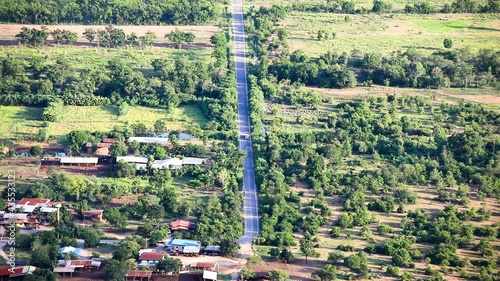 A straight road with a moving truck in Lopburi, Thailand from a viewpoint overlooking the landscape and small village with a static shot in HD. photo