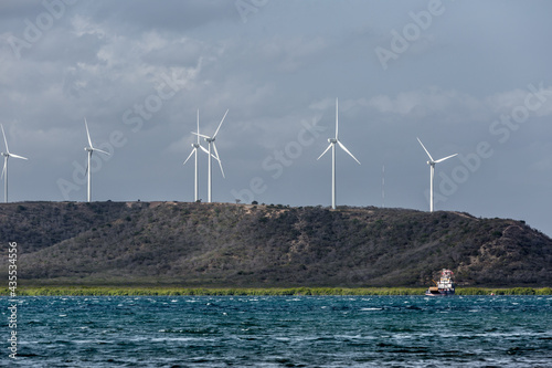 Dramatic image of windmills for power on the hillside off the Caribbean coast of the Dominican Republic., with Caribbean Sea in the foreground.