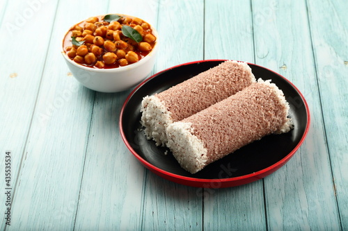 Homemade delicious steamed red rice puttu served with chickpeas curry, Kerala foods background.