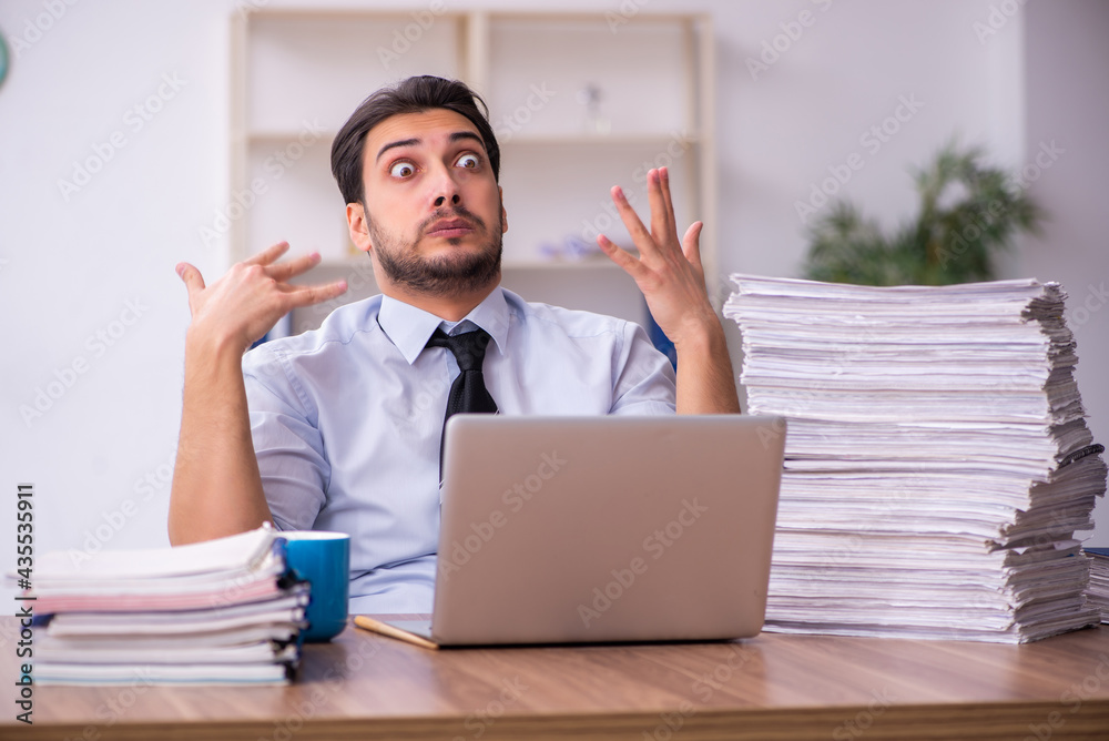Young businessman employee unhappy with excessive work in the office Young businessman employee unhappy with excessive work in the office