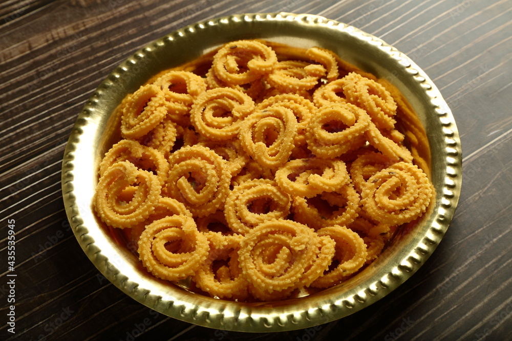 Indian snack foods- delicious crispy fried spicy chakli, chakkli, murukku served in brass plate. Indian snack foods- delicious crispy fried spicy chakli, chakkli, murukku served in brass plate.