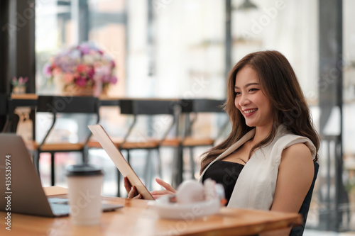 Happy asian beautiful woman working on a laptop for online group meeting at cafe