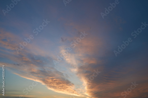 Beautiful evening blue sky at sunset with flaming bright light clouds. A warm summer evening at sunset. Bright sunset © nikolay_alekhin