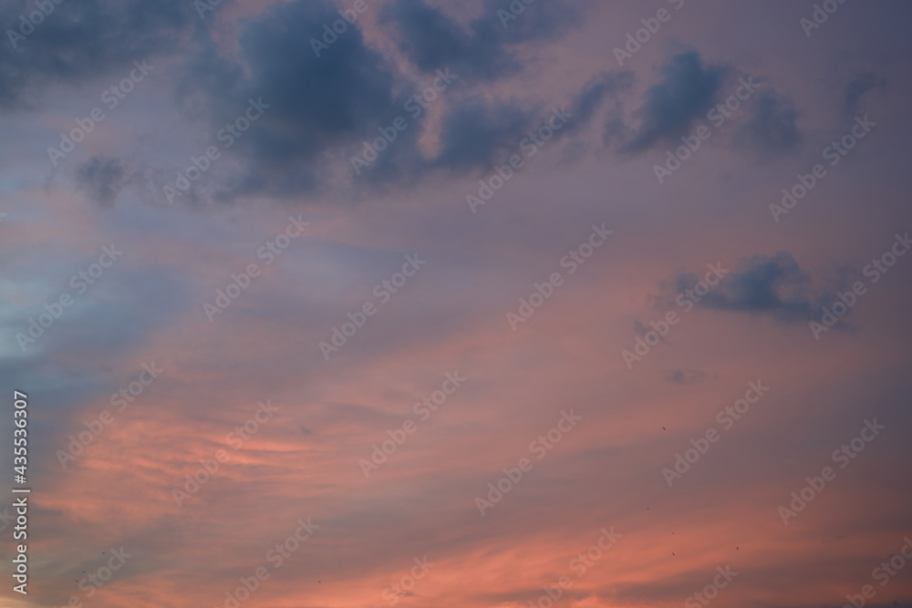 Beautiful evening blue sky at sunset with flaming bright light clouds. A warm summer evening at sunset. Bright sunset