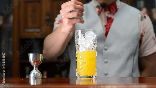 Bartender showing cocktail in a tiki glass on a bar counter on a blurred background of bottles in a bar photo