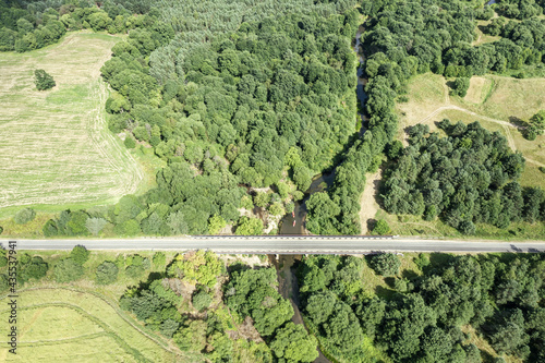 aerial view of a highway with bridge going through the green summer forest and farmland