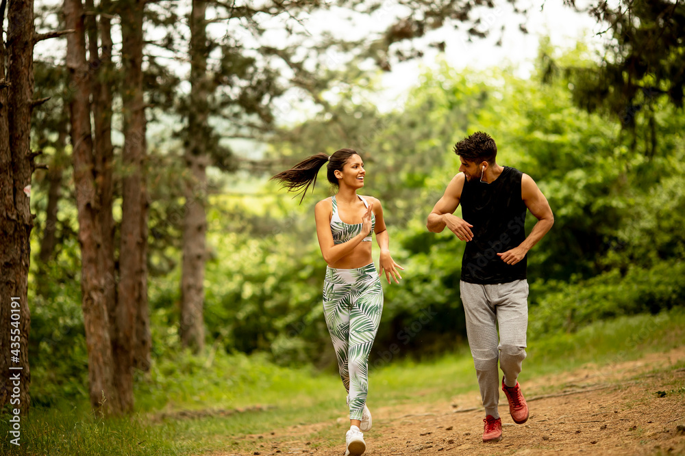 Young fitness couple running at the forest trail