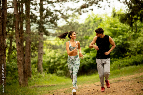 Young fitness couple running at the forest trail