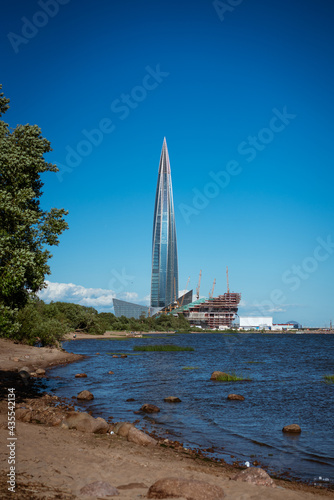 beautiful tall building on the shore of the bay, glass facade against the blue sky. Architecture in the city