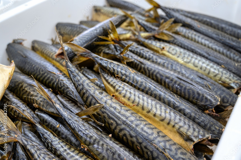 Lots of smoked mackerel carcasses. The fish lies in a heap in a white plastic box. Lots of smoked mackerel carcasses. The fish lies in a heap in a white plastic box.