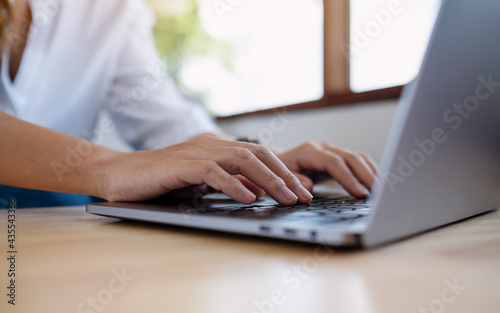 Closeup image of a woman working and typing on laptop computer keyboard on the table