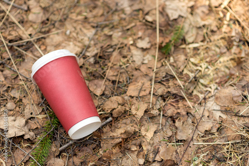 Paper cup with coffee or drink outdoor on a background of forest nature.People left behind trash.copy space.