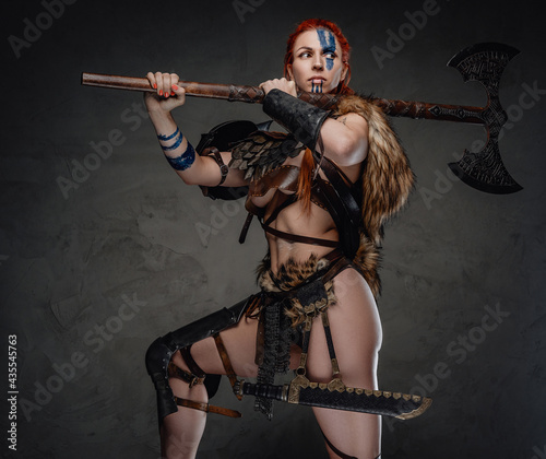 Foto Sexy and muscular woman viking holding an axe on her shoulder