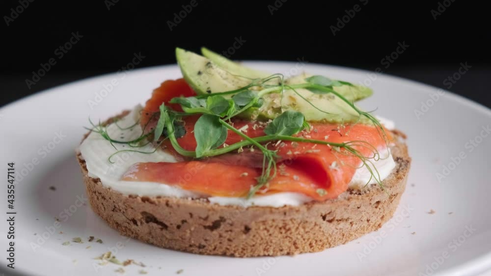 Breakfast toast with cream cheese, salmon and avocado, black background. Breakfast toast with cream cheese, salmon and avocado, black background.