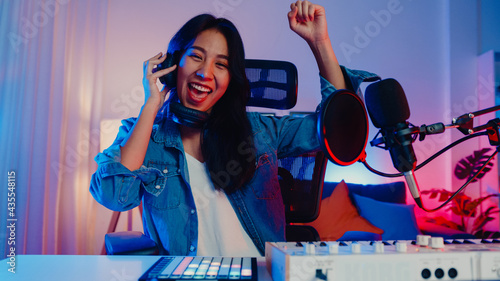 Quadro su tela Happy asia girl dj play launchpad synthesizer keyboard sound mixer wear headphone and performance music online live talk with audience in living room home studio at night