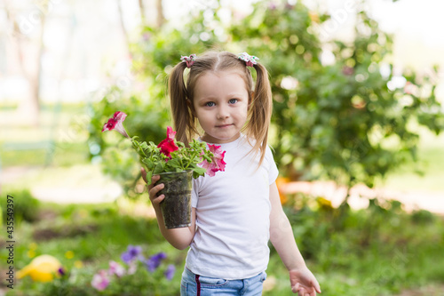 child girl plant flowers in the garden near the houme on spring day. Kid help mom work in the garden. slow life. enjoy the little things. 