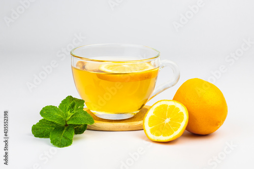 Transparent glass cup with aromatic tea, mint leaves and lemon slice isolated on white background. Part of set.