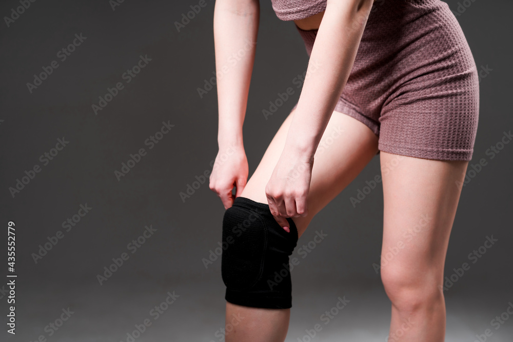 Women's legs with a knee pad for rehabilitation after injuries. Close-up. Isolated on white background