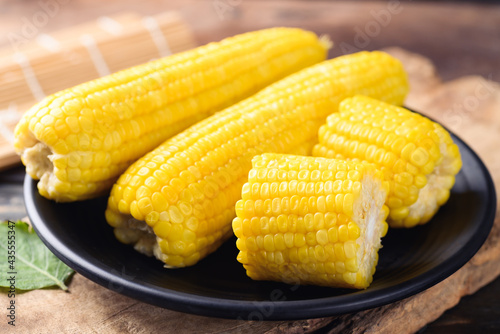Sweet corn cob on black plate with wooden background