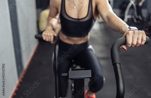 Woman doing intense cardio training on exercise bike. Fitness female using air bike for cardio workout at gym