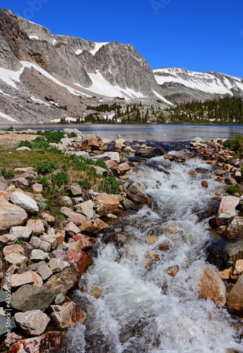 pretty lake marie and a small cascade on a sunny summer day  against a backdrop of  the medicine bow peaks in the medicine bow national forest in southeastern wyoming 