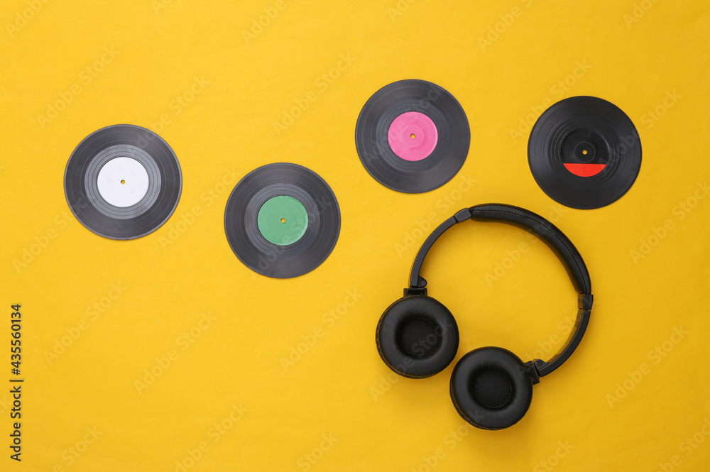 Musical layout. Headphones and vinyl records on yellow background. Top view. Flat lay