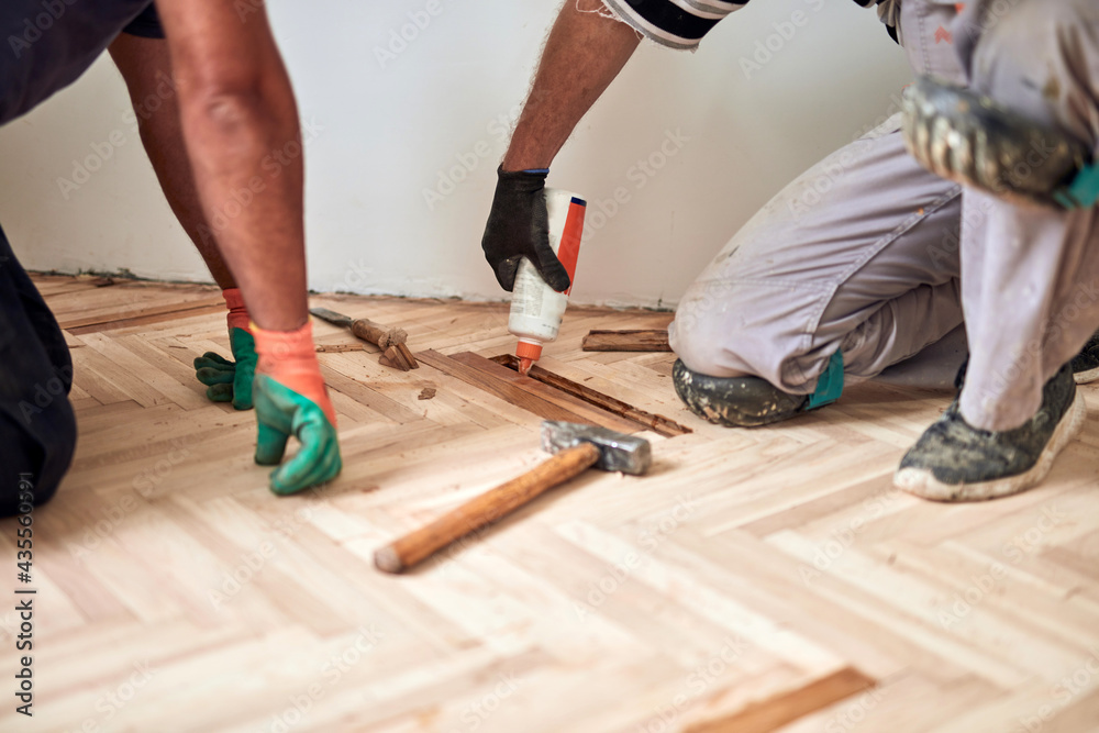 Repairman restoring parquet with a sanding machine.