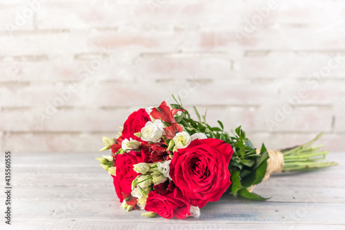 bouquet of red and white roses with alstroemeria on a light rustic brick background