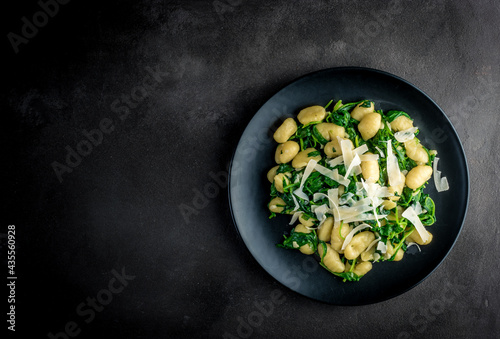 gnocchi with spinach and parmesan on a dark background with copy space