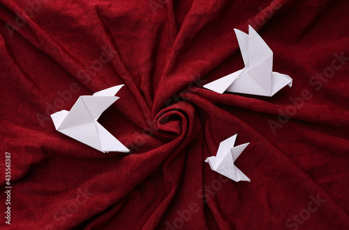 Origami doves on red silk background photo