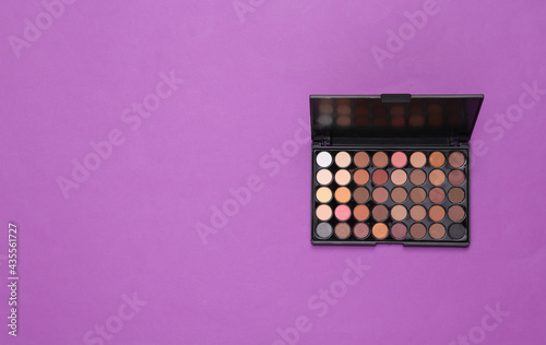 Bright make up eye shadow pallete on purple background. Beauty still life. Top view. Flat lay