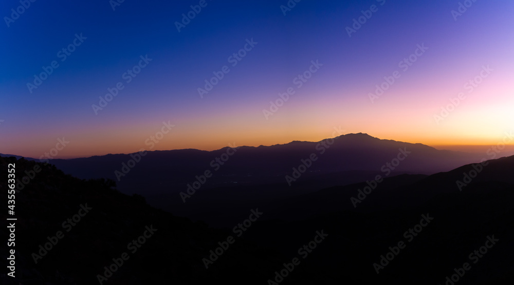 Wide shot of hills silhouette at sunset colorful, blue, orange and purple sky in joshua tree in america