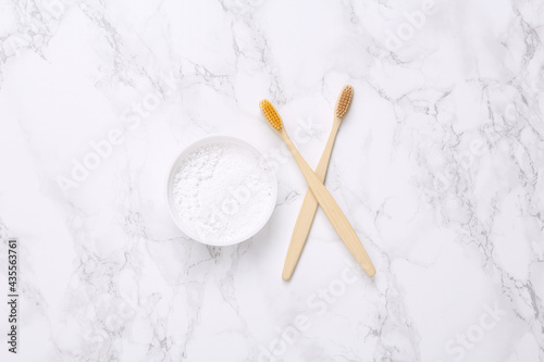 Eco-friendly bamboo toothbrushes and tooth-powder on marble background. Top view.
