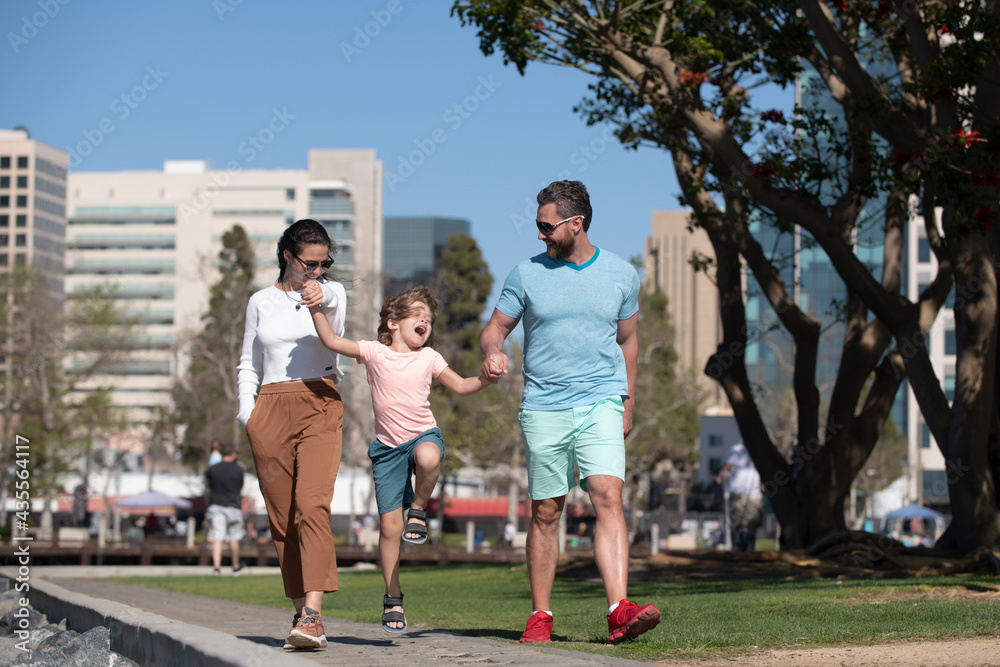 Obraz premium Parents with son walking in the city. Family taking a walk on street outdoors against city landscape