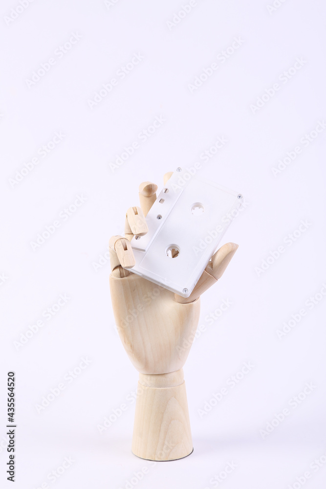 Wooden hand holding audio cassette on white background