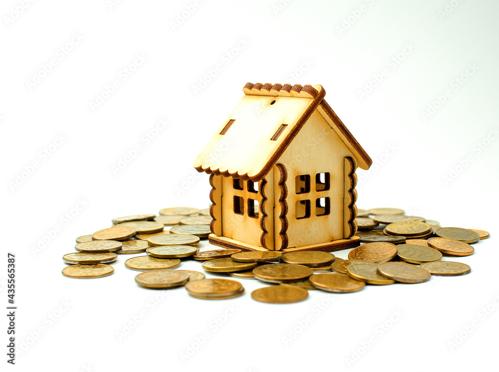 Miniature wooden house stands on top of metal coins, isolated on a white background. Concept of buying and selling apartments, houses. Real estate object. Copy space. Selective focus. Miniature wooden house stands on top of metal coins, isolated on a white background. Concept of buying and selling apartments, houses. Real estate object. Copy space. Selective focus.