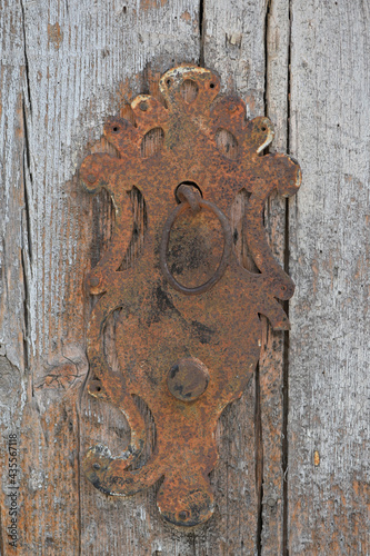 An old and rusty door fitting in Spain. Partial view of an historic entrance door.