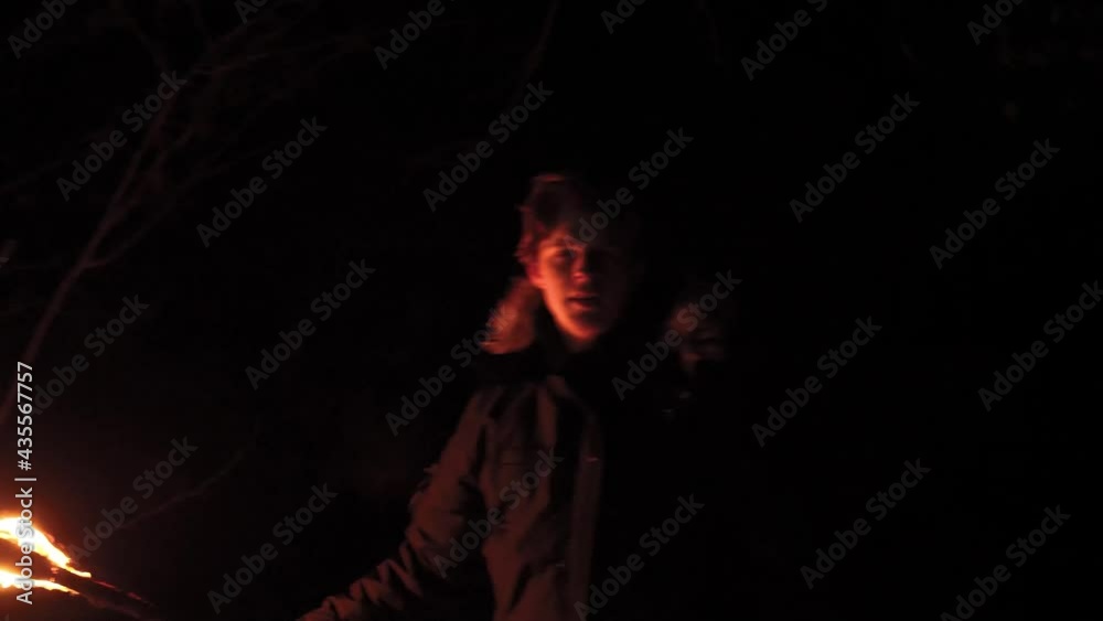 Scared man in night forest fears for an attack waving a torch trying to protect. Suspense atmosphere