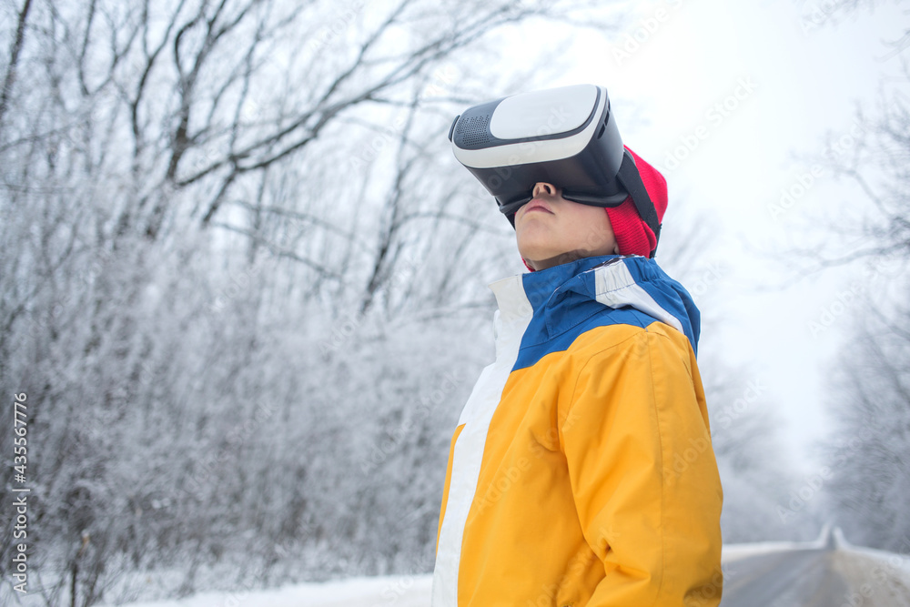 Boy in virtual reality glasses in winter scenery on the road Boy in virtual reality glasses in winter scenery on the road