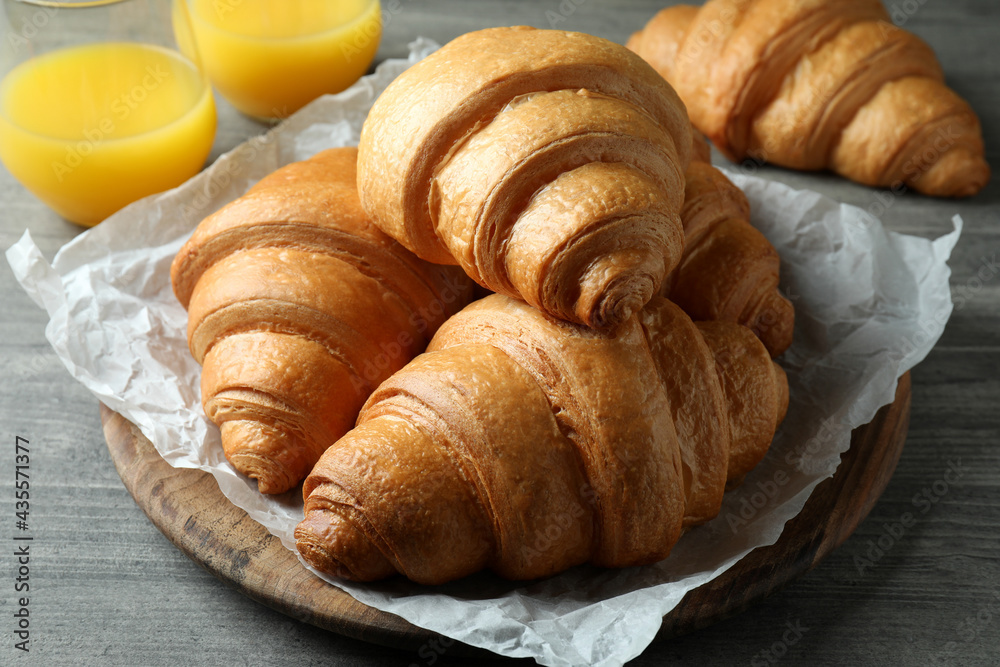 Tasty croissants and juice on gray textured table