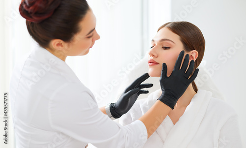 Cosmetologist in gloves checking face of woman photo