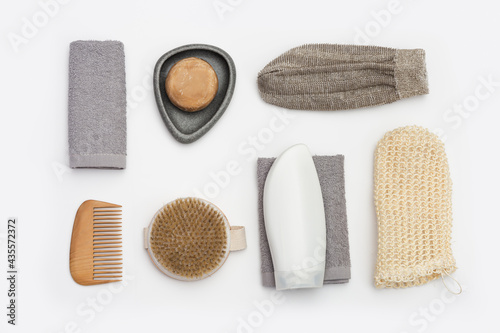 Flat lay composition with bath accessories with bottls with gel or shampoo, soap, washcloth, wooden comb on white